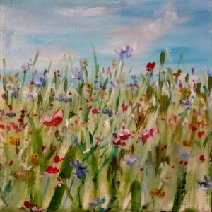 A meadow of flowers in shades of yellow, red and blue, a clear sky above.